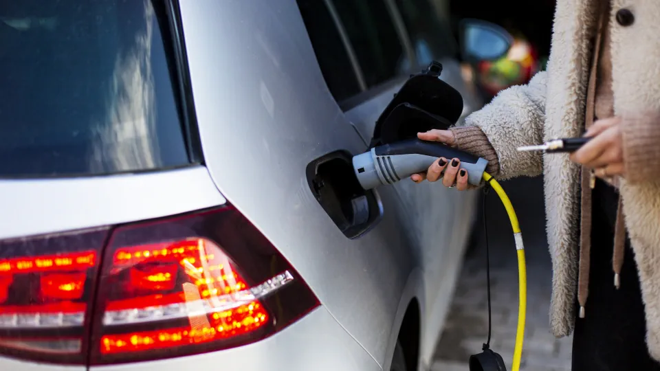 Klima-Schutz: Eine Frau hält das Ladekabel einer Strom-Zapfsäule an den Anschluss eines E-Autos.